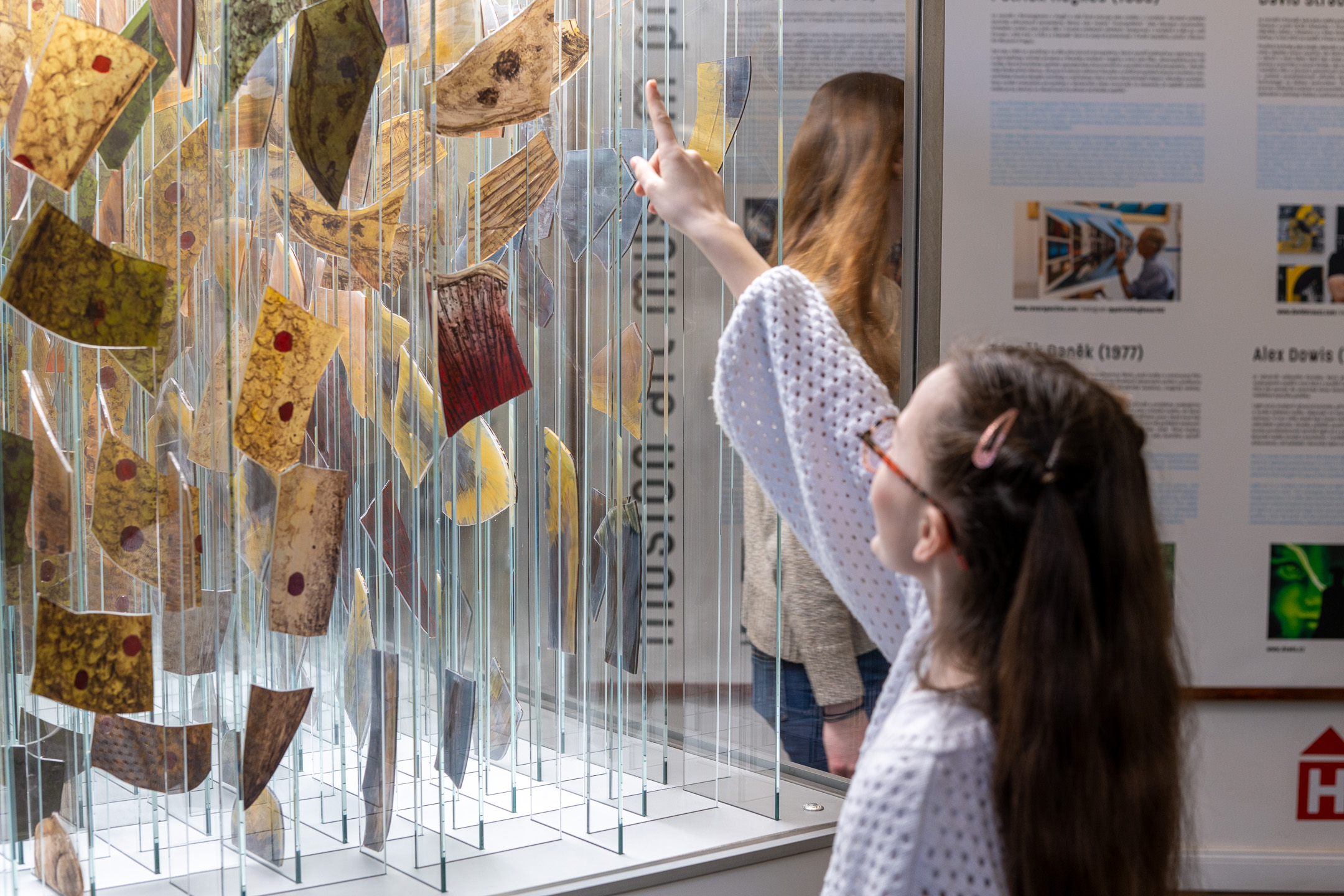 Girl points at colourful fragments suspended on vertical glass panes