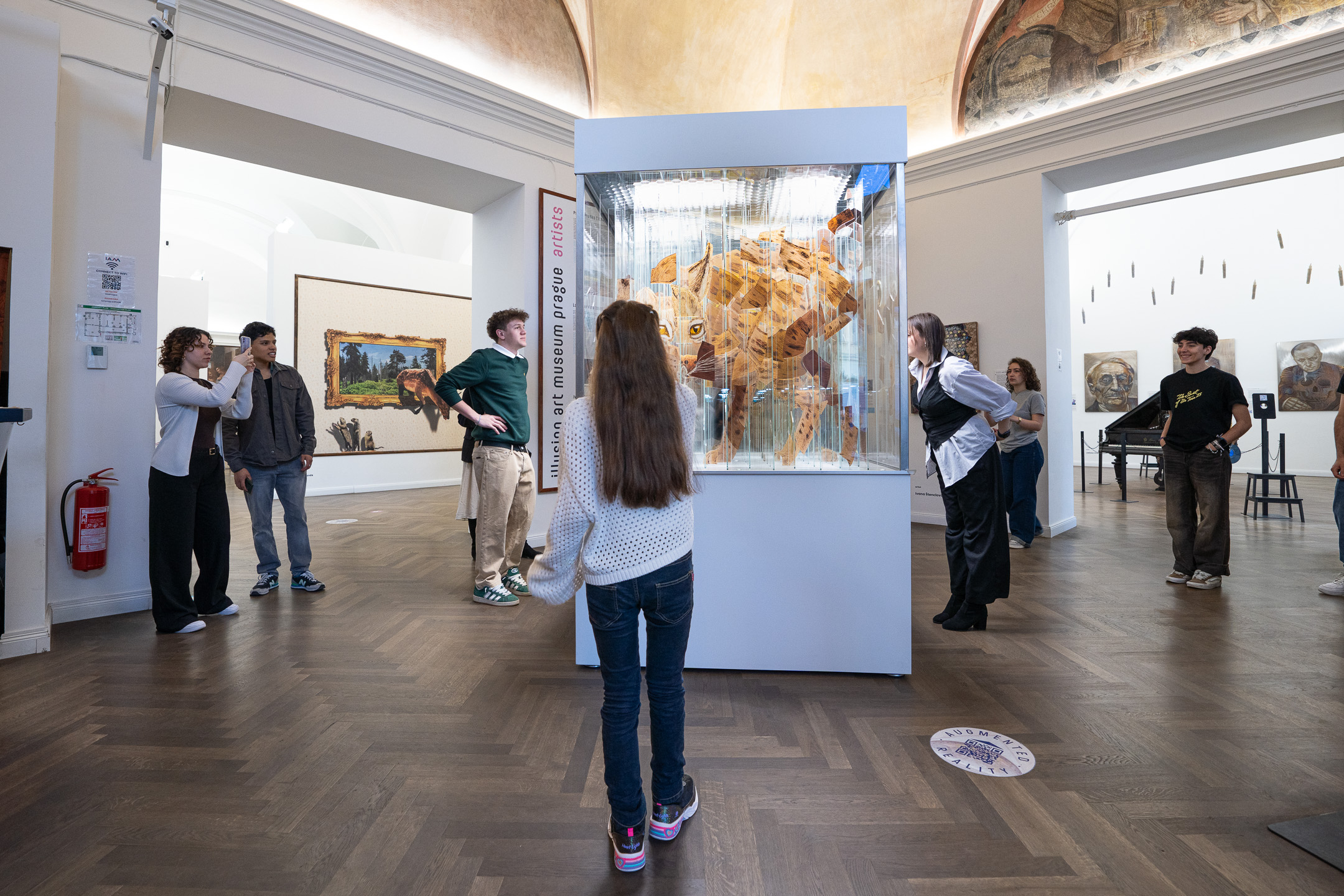 Visitors around a glass case holding a layered lynx sculpture
