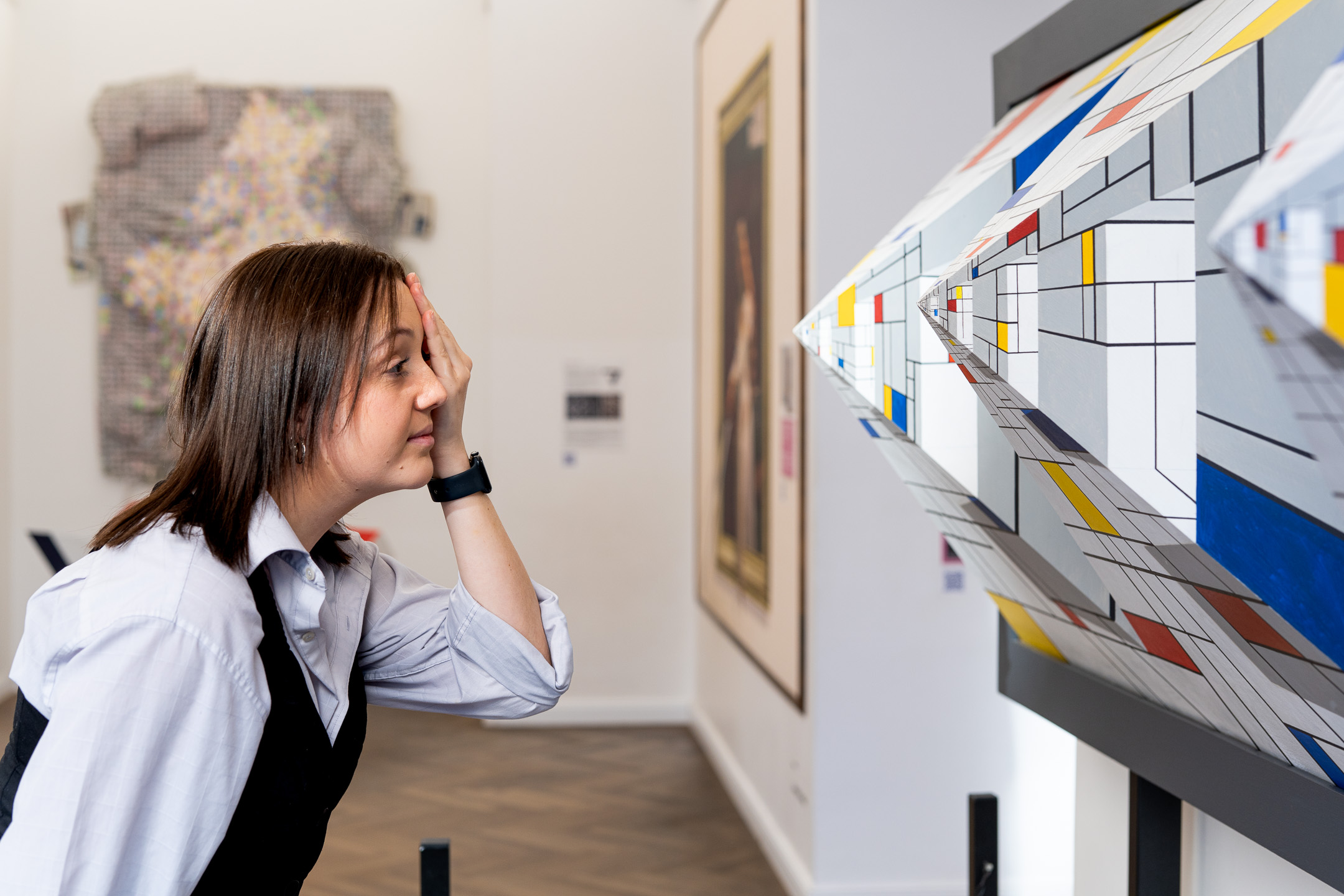 Visitor covers one eye to view a Mondrian-style 3D perspective artwork