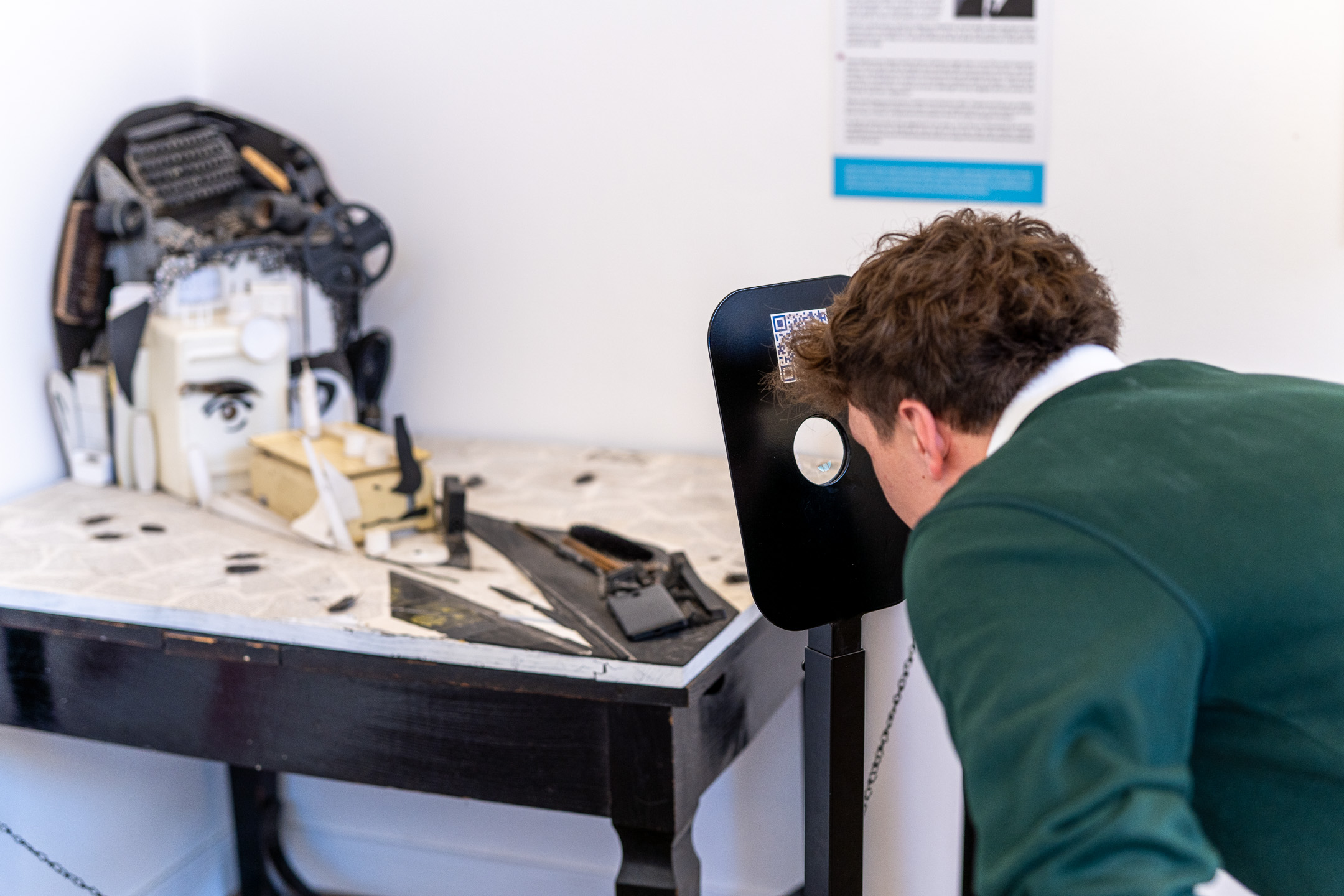 Visitor looks through a viewer at an assemblage face on a table