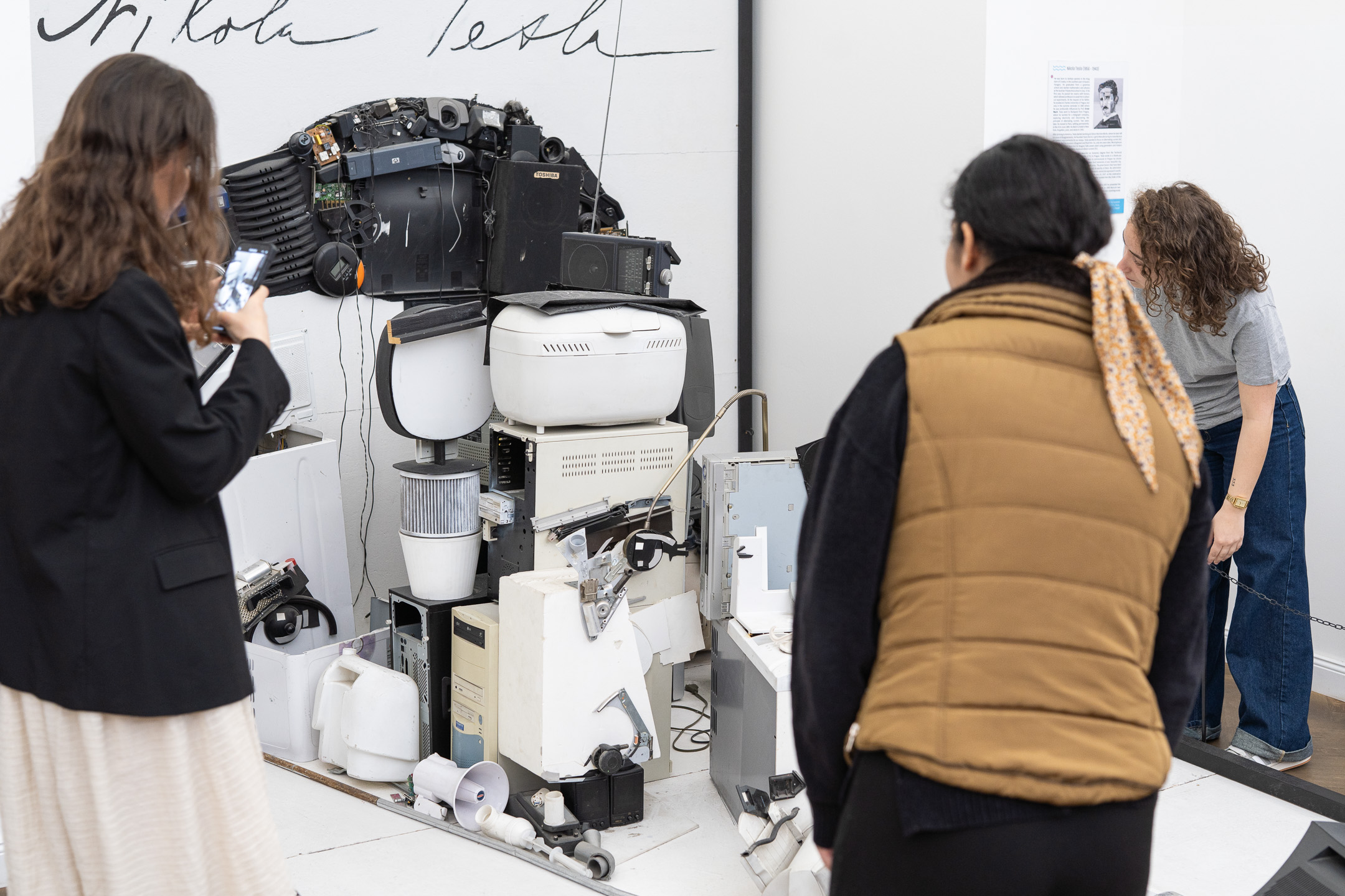 Visitors photograph a Nikola Tesla portrait built from old electronics